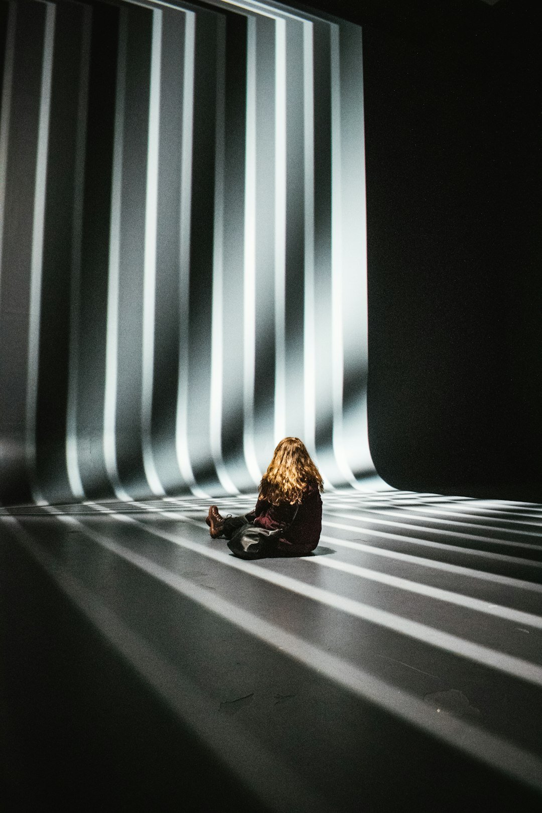 a-woman-sitting-on-the-ground-in-front-of-a-wall-b5piahy2dng