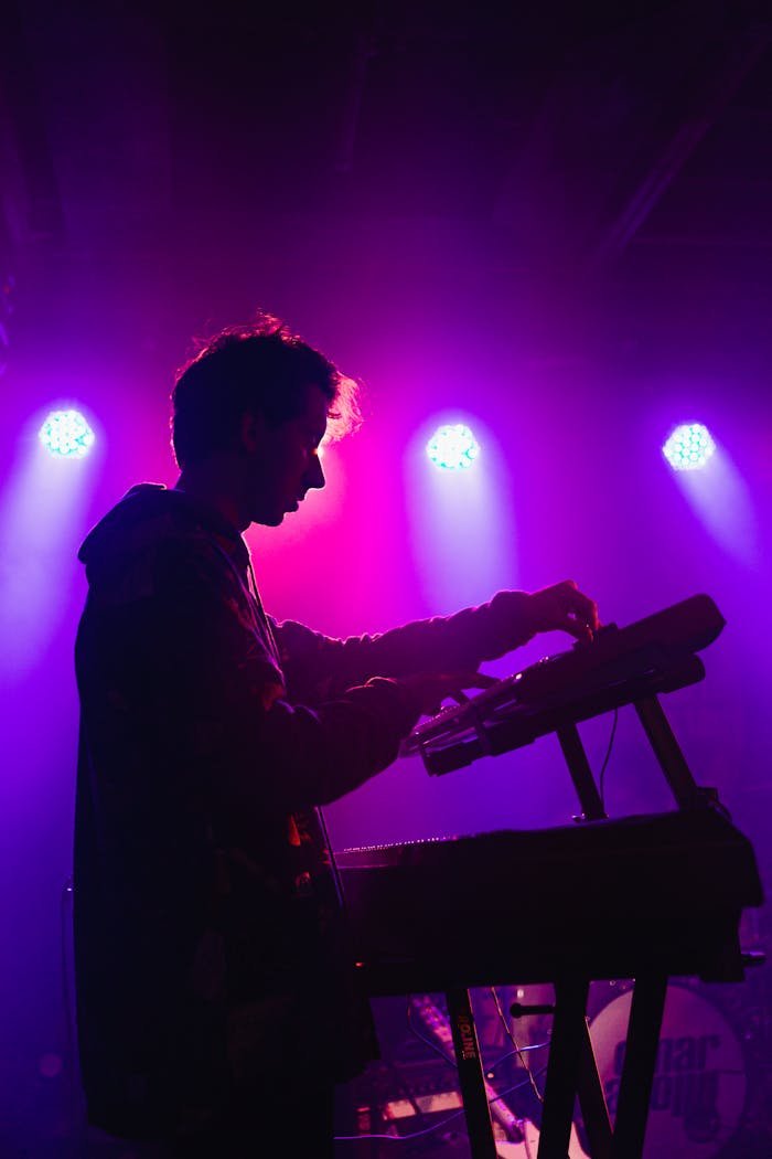 A DJ mixing music on stage with vibrant purple lighting creating a moody atmosphere.